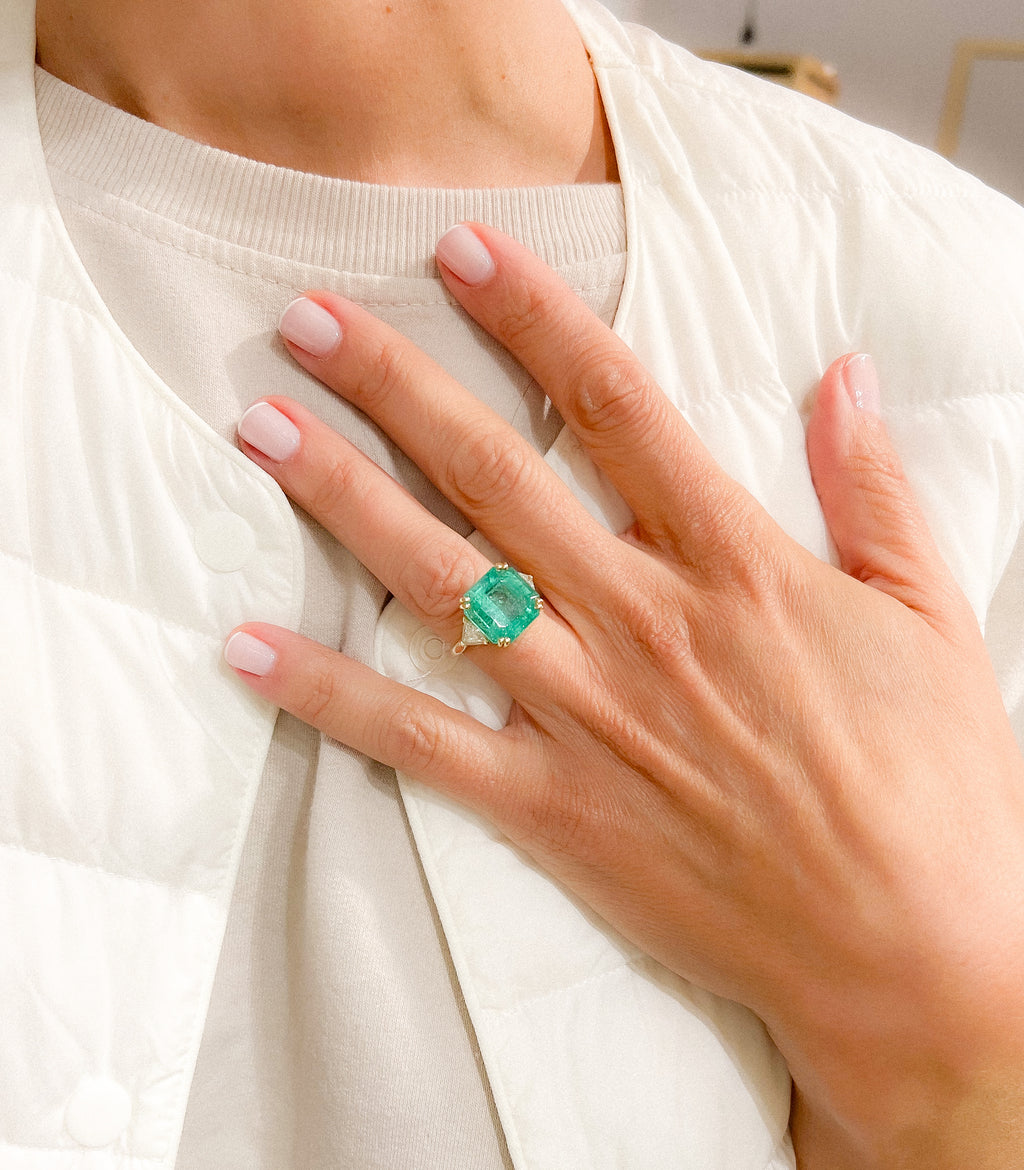 Yellow gold ring adorned with an emerald-cut emerald flanked by triangle diamonds