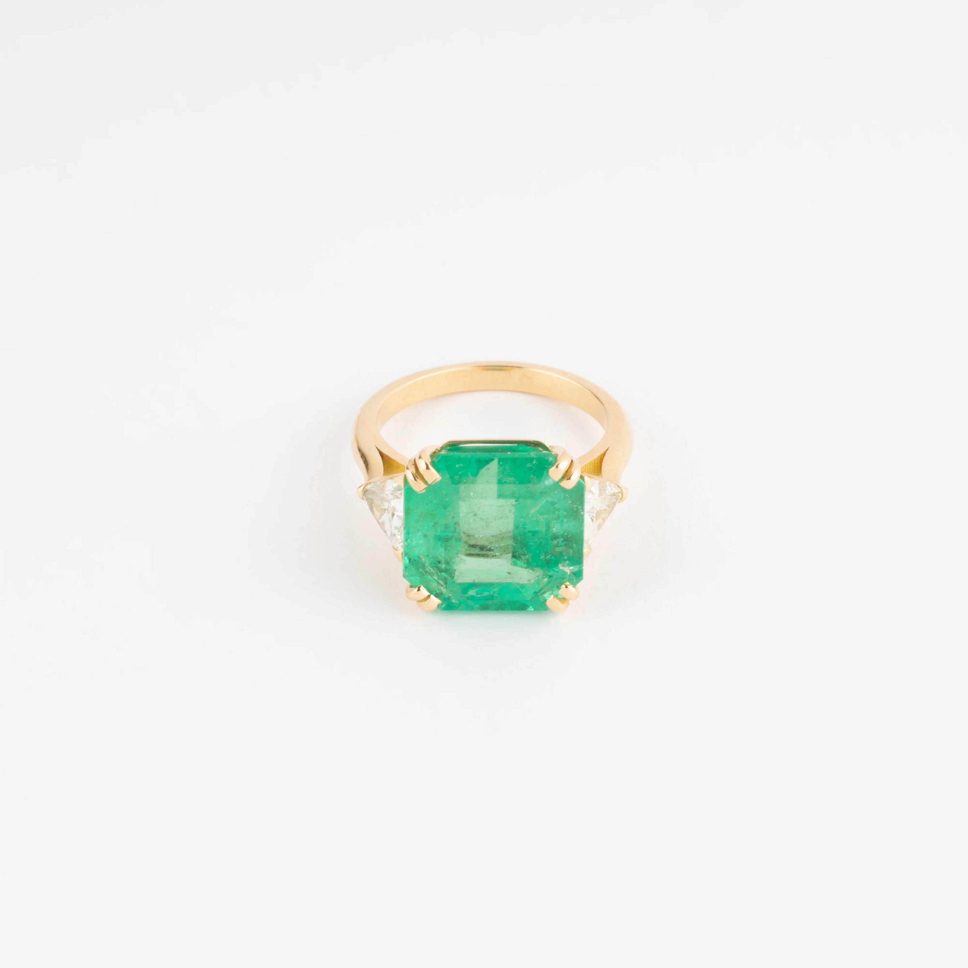 Yellow gold ring adorned with an emerald-cut emerald flanked by triangle diamonds