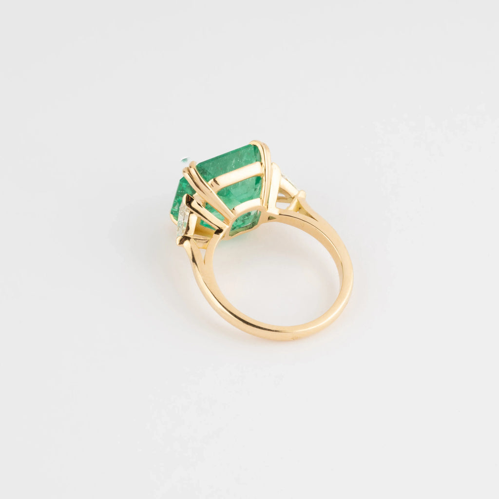 Yellow gold ring adorned with an emerald-cut emerald flanked by triangle diamonds