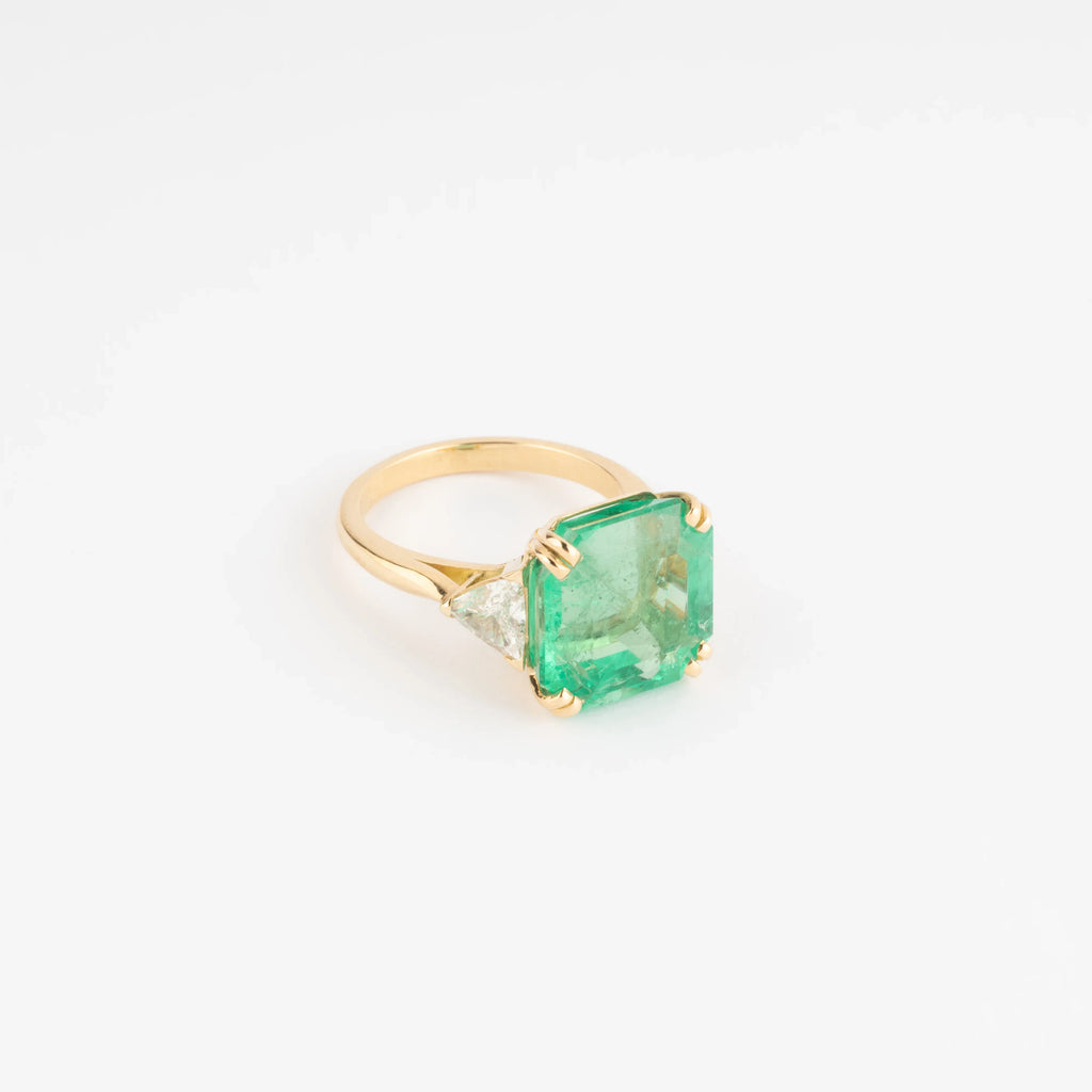 Yellow gold ring adorned with an emerald-cut emerald flanked by triangle diamonds
