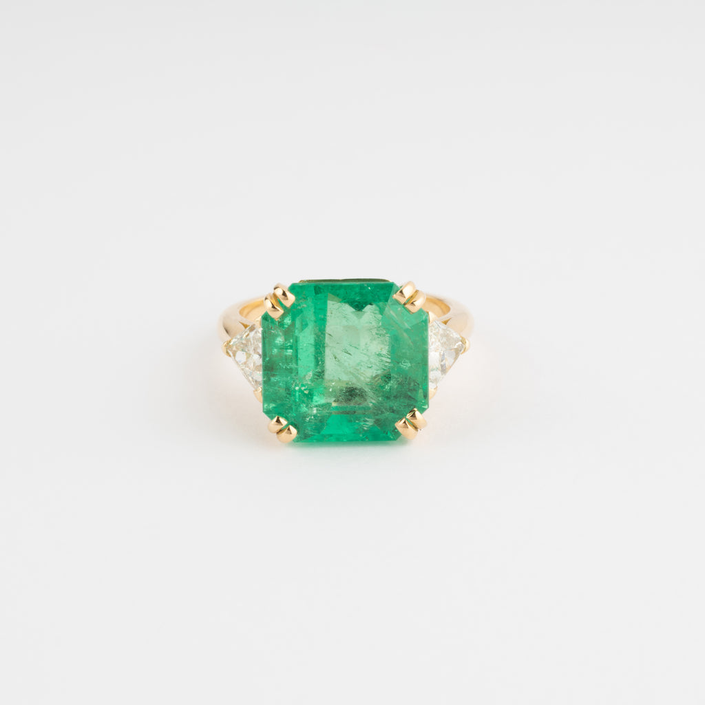Yellow gold ring adorned with an emerald-cut emerald flanked by triangle diamonds