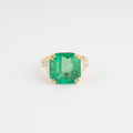 Yellow gold ring adorned with an emerald-cut emerald flanked by triangle diamonds