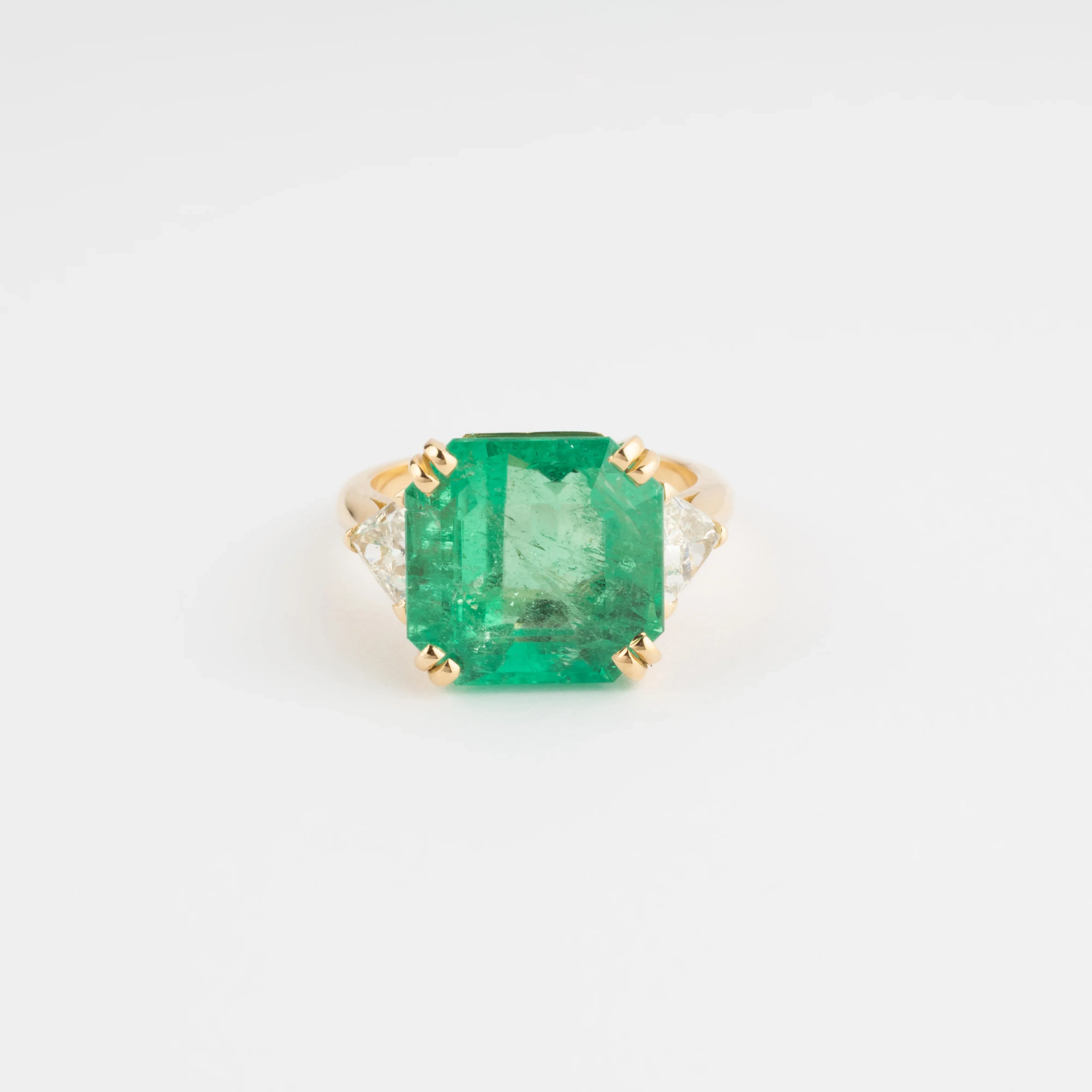 Yellow gold ring adorned with an emerald-cut emerald flanked by triangle diamonds