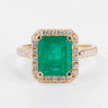 Yellow gold ring adorned with an emerald surrounded by diamonds