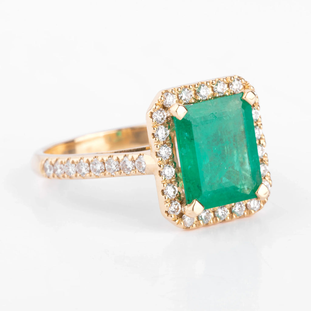 Yellow gold ring adorned with an emerald surrounded by diamonds