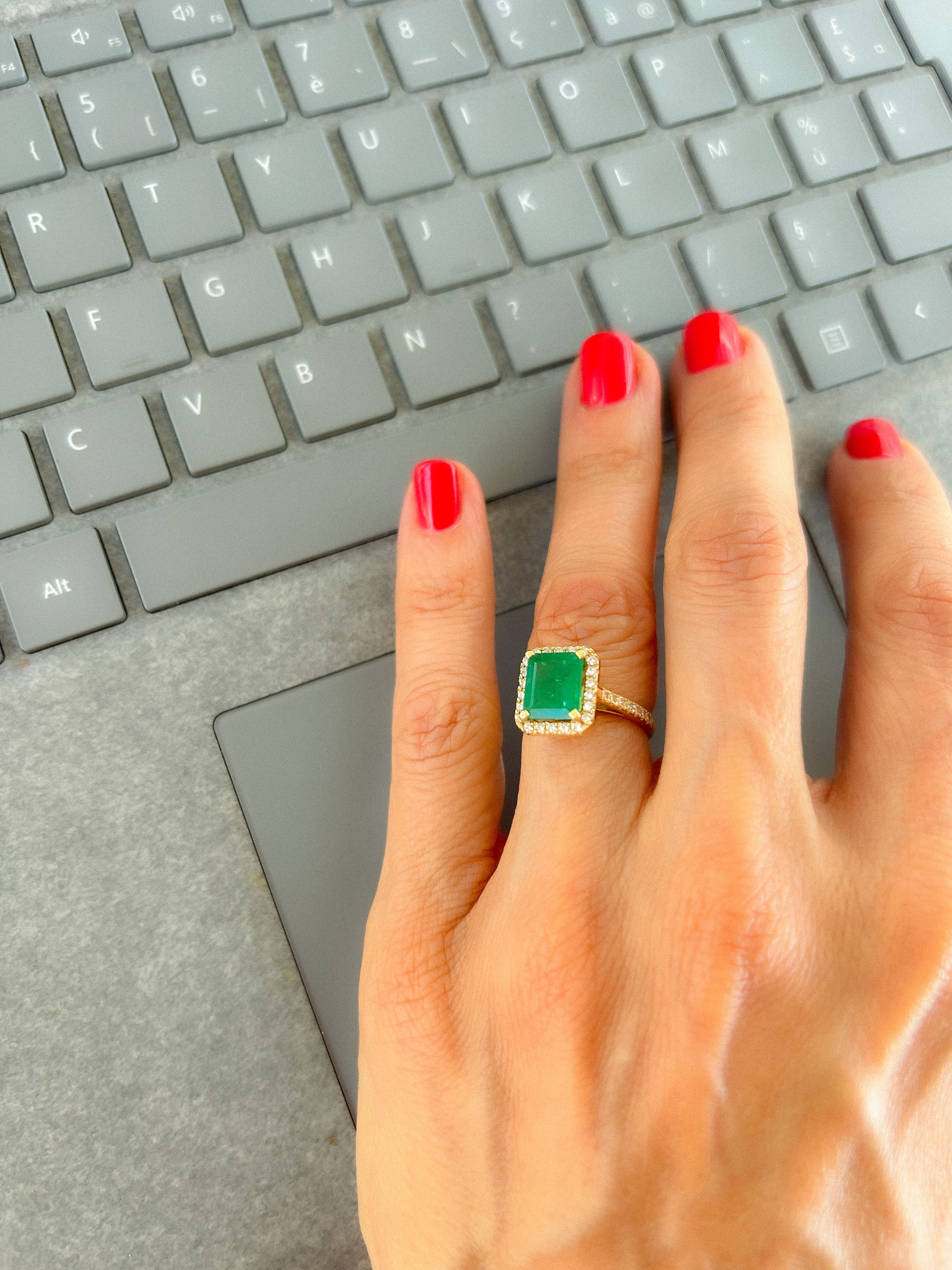Yellow gold ring adorned with an emerald surrounded by diamonds